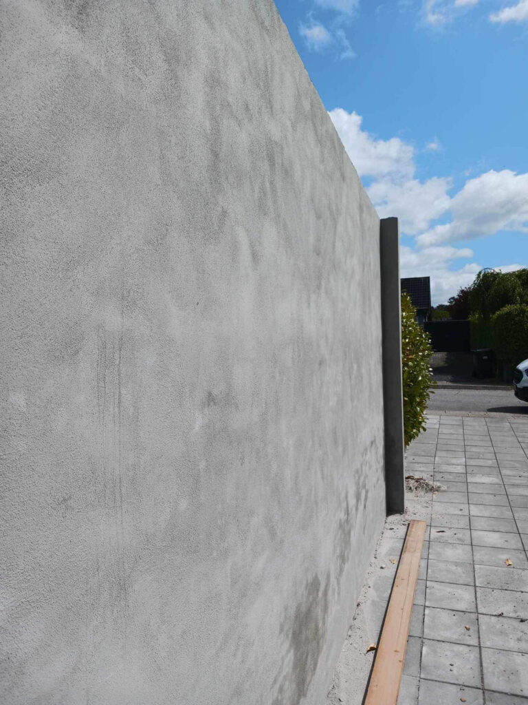 Ny pudset mur ved flisebelagt gangsti